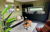 Modern lodge Modus Wellness 2 at Zuiderzee, Netherlands, living room with kitchen, sofa, and plants.