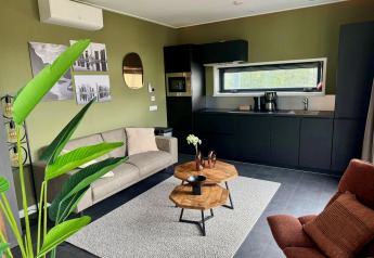 Moderne lodge Modus Wellness 2 aan het Zuiderzee in Nederland, leefruimte met keuken, zetel en planten.