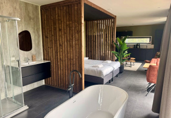 Moderne Lodge Modus Wellness 2 am Zuiderzee, Niederlande, mit freistehender Badewanne, Bett und Küche.