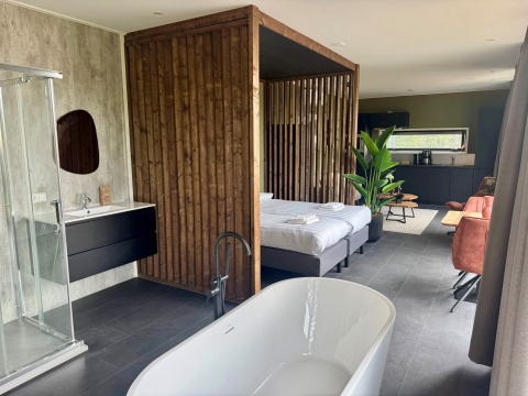 Moderne Lodge Modus Wellness 2 am Zuiderzee, Niederlande, mit freistehender Badewanne, Bett und Küche.