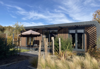 Modus Wellness 2 lodge aan Zuiderzee in Nederland, moderne bouwstijl met terras en natuurlijke tuin.