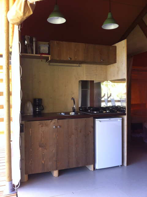 Kleine Küchenzeile mit Holzmöbeln, Gasherd und Minikühlschrank im Safari-Zelt auf Camping Podere sei Poorte.