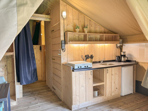 Interieur van een safaritent met houten keuken bij Horsens City Camp in Denemarken.