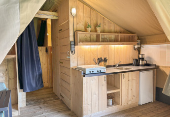 Indvendigt køkken og træinteriør i en safariteltsuite på Horsens City Camp i Danmark.