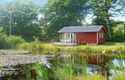 Casa vacanze rossa vicino a uno stagno, tra alberi verdi a Smedstorp, in Svezia.