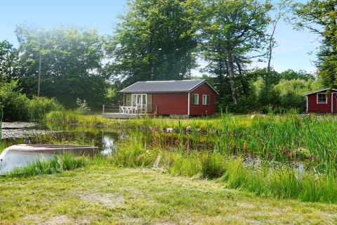 Acogedora casa de vacaciones para 4 personas en Smedstorp, rodeada de naturaleza y un estanque con bote.
