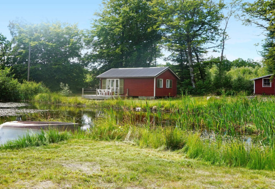 Acogedora casa de vacaciones para 4 personas en Smedstorp, rodeada de naturaleza y un estanque con bote.