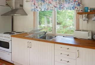 Cocina luminosa y acogedora en una casa de vacaciones para 4 personas en Smedstorp, Suecia, con encimera de madera.
