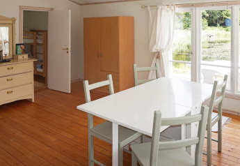 Lichte eetkamer in vakantiehuis in Smedstorp, Zweden, met wit meubelair en zicht op de vijver.