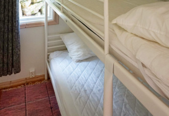 Camera con letto a castello, lenzuola e cuscini bianchi vicino a una finestra in un lodge a Smedstorp, Svezia.