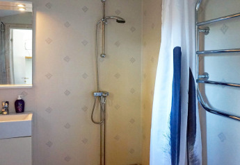 Salle de bain avec douche, lavabo, miroir et porte-serviettes dans une maison de vacances à Smedstorp, Suède.