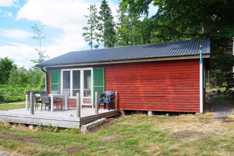 Casa vacanze rossa con persiane verdi, veranda e mobili da esterno a Smedstorp, nella campagna svedese.