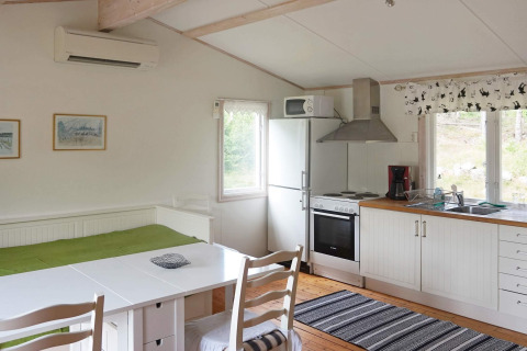 Gemütliches Ferienhaus in Smedstorp, Schweden, mit Küche, Essbereich, Bett und großen Fenstern.