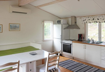 Gemütliches Ferienhaus in Smedstorp, Schweden, mit Küche, Essbereich, Bett und großen Fenstern.