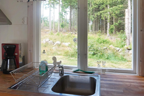 Küche mit Spüle, Geschirrkorb, Kaffeemaschine und Ausblick auf den Wald durch Fenster in Smedstorp, Schweden.