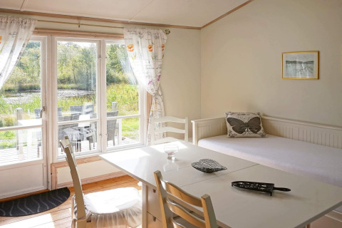 Salon lumineux dans une maison de vacances à Smedstorp, Suède, avec accès terrasse et vue sur l’étang.