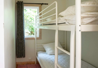 Helles Zimmer mit Etagenbett und Fenster im 4-Personen-Ferienhaus in SMEDSTORP, Schweden.