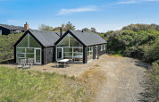 Casa de vacaciones moderna en Blokhus, Dinamarca, con grandes ventanales y patio exterior amueblado.