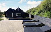 Terrasse extérieure du gîte pour 6 personnes à Blokhus, Danemark, avec transats et clôture noire.