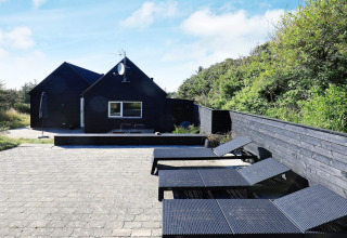 Terras bij 6-persoons vakantiehuis in Blokhus, Denemarken, met ligstoelen en zwart houten hek.