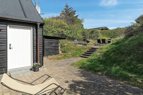 Terras met ligstoel, treden en eetgedeelte bij een vakantiehuis in Blokhus, Denemarken op zonnige dag.