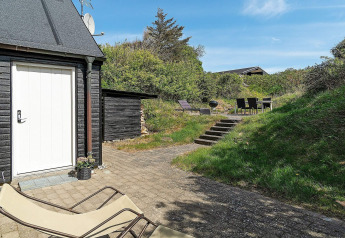 Terras met ligzetel, trappen en eethoek bij een vakantiehuis in Blokhus, Denemarken op zonnige dag.