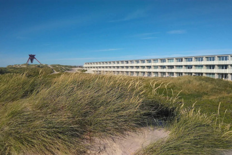 Udsigt over klitter og det moderne feriehus '6 personers feriebolig i Blokhus' i Danmark på en solskinsdag.