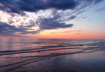 Tramonto sul mare visto da un lodge, onde leggere e colori vibranti del cielo riflessi sull'acqua.