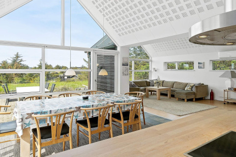 Lichte en moderne woonkamer in vakantiehuis in Blokhus, Denemarken, met eettafel en zithoek.