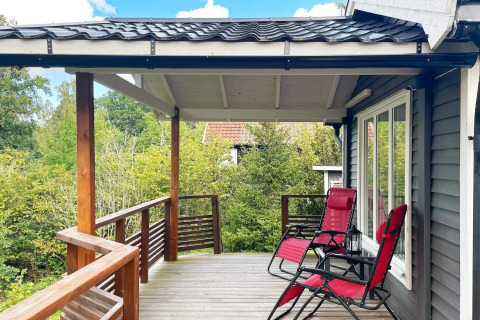 Houten terras met twee rode ligzetels bij een vakantiehuis in Gränna, Zweden, omgeven door natuur.