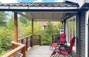 Terrazza in legno con due sedie a sdraio rosse in una casa vacanze a Gränna, Svezia, immersa nel verde.