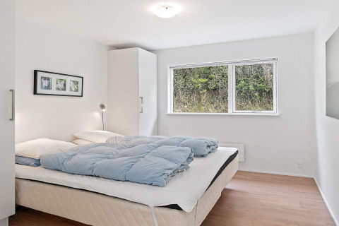 Lichte, minimalistische slaapkamer met groot bed en natuurzicht in een vakantiehuis in Blokhus, Denemarken.