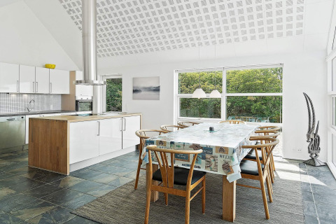 Moderne keuken en eetruimte in een vakantiehuis in Blokhus, Denemarken, met grote ramen en boszicht.