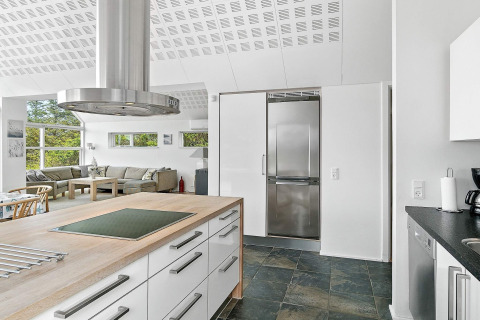 Moderne Küche und Wohnzimmer in einem Ferienhaus in Blokhus, Dänemark, mit hellen Fenstern.