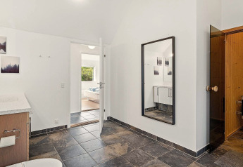 Salle de bain moderne dans une maison de vacances à Blokhus, Danemark, avec carrelage, miroir et sauna.