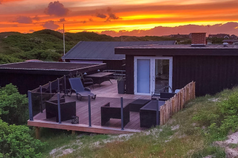 Sonnenuntergang über der Terrasse der „Seaside Charm in Rindby“-Lodge in Dänemark mit moderner Einrichtung.