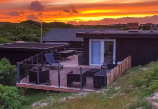 Sonnenuntergang über der Terrasse der „Seaside Charm in Rindby“-Lodge in Dänemark mit moderner Einrichtung.