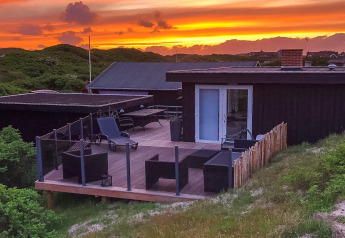 Sonnenuntergang über der Terrasse der „Seaside Charm in Rindby“-Lodge in Dänemark mit moderner Einrichtung.