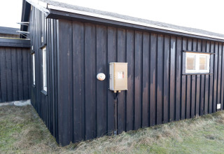 Außenansicht der Seaside Charm in Rindby Lodge in Dänemark mit schwarzen Holzpanelen und Fenster.