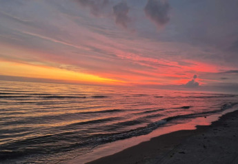 Sonnenuntergang am Meer bei ruhigen Wellen, gesehen am Seaside Charm in Rindby, Dänemark.
