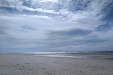 Spiaggia tranquilla sotto un cielo nuvoloso, fotografata da un lodge con vista sulla costa serena.