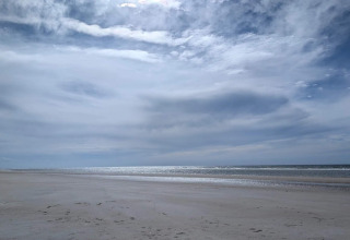 Spiaggia tranquilla sotto un cielo nuvoloso, fotografata da un lodge con vista sulla costa serena.