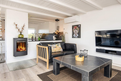 Helles, modernes Wohnzimmer in Seaside Charm in Rindby, Dänemark, mit Kamin, Sofa und Fernseher.
