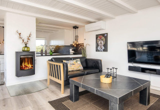 Helles, modernes Wohnzimmer in Seaside Charm in Rindby, Dänemark, mit Kamin, Sofa und Fernseher.