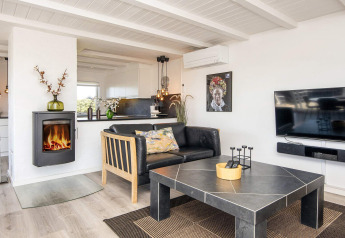 Helles, modernes Wohnzimmer in Seaside Charm in Rindby, Dänemark, mit Kamin, Sofa und Fernseher.