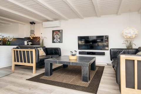 Helles Wohnzimmer in Seaside Charm in Rindby, Dänemark, mit schwarzem Sofa, TV und modernem Design.