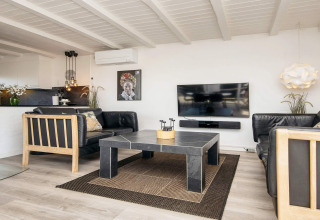 Helles Wohnzimmer in Seaside Charm in Rindby, Dänemark, mit schwarzem Sofa, TV und modernem Design.