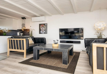 Helles Wohnzimmer in Seaside Charm in Rindby, Dänemark, mit schwarzem Sofa, TV und modernem Design.