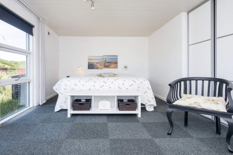 Helles Schlafzimmer in der Lodge 'Seaside Charm in Rindby', Dänemark, mit Doppelbett und Fenster.