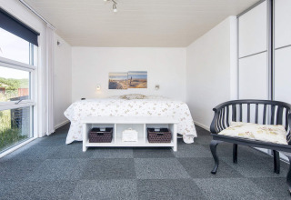 Helles Schlafzimmer in der Lodge 'Seaside Charm in Rindby', Dänemark, mit Doppelbett und Fenster.